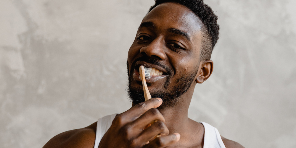A man brushing his teeth at home with a smile