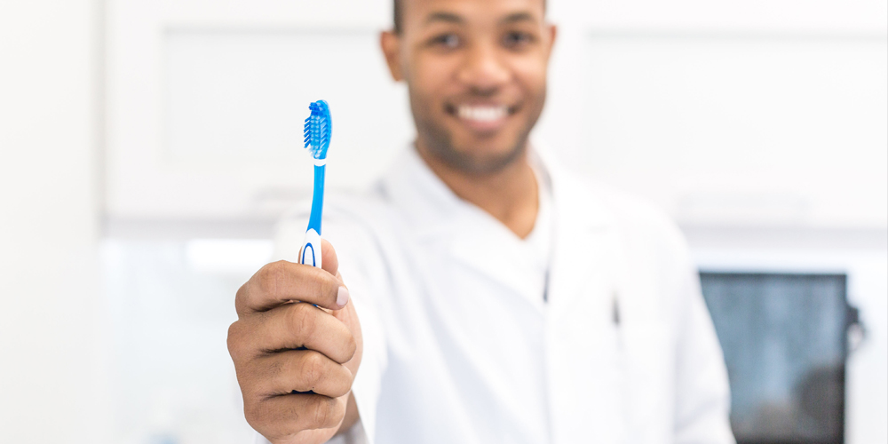 A dentist holding up a tooth brush to ensure his patients understand regular brushing and flossing is needed to ensure the longevity of your dental inlays