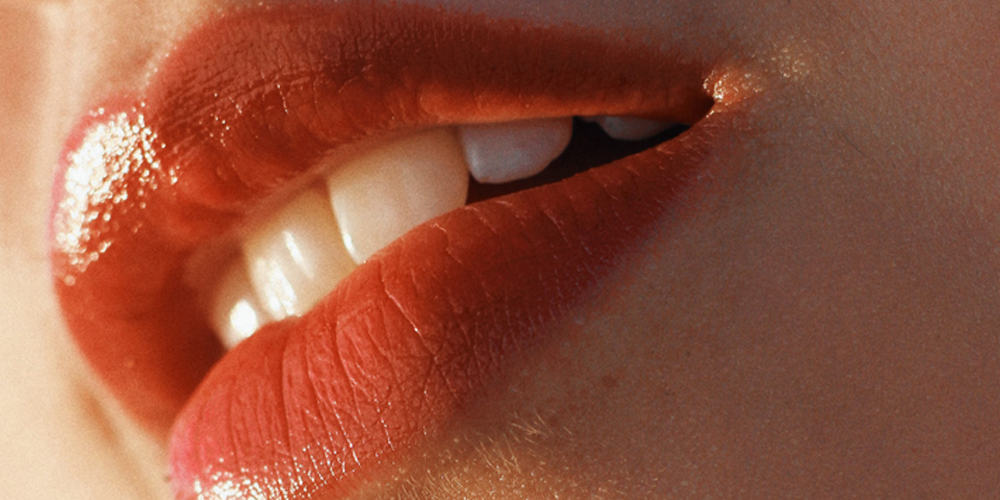 A womens mouth with red lipstick showing her white veneers