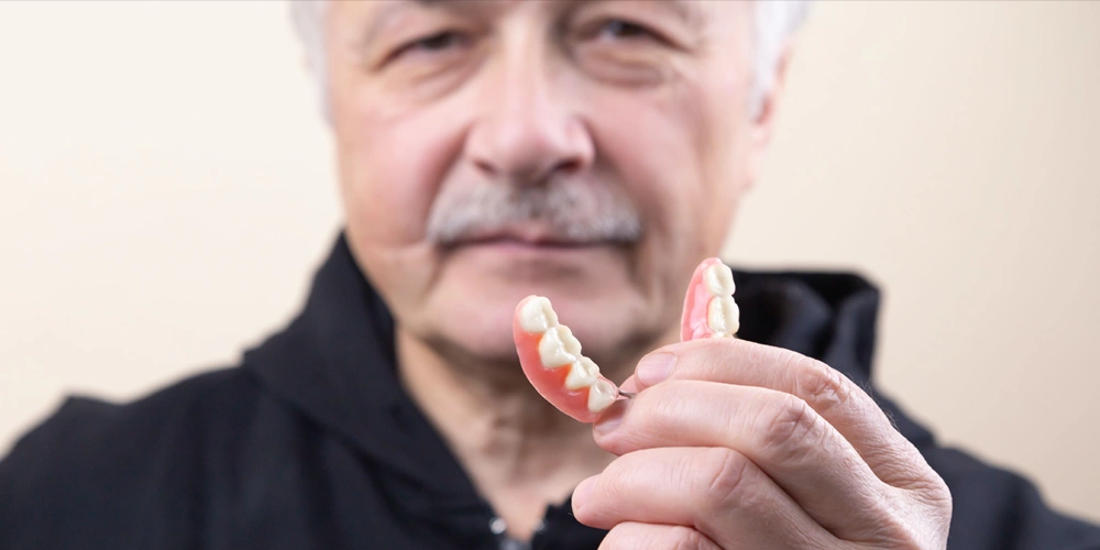 A man holding his partial dentures