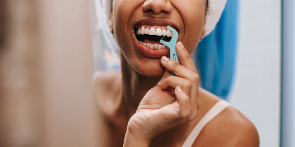 A women flossing her teeth to prevent plaque