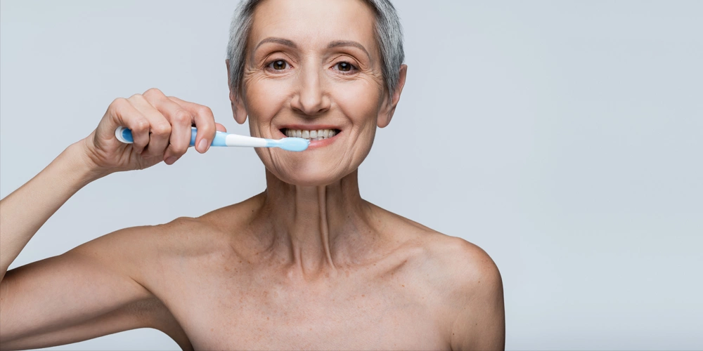 A women brusing her dentures after the procedure