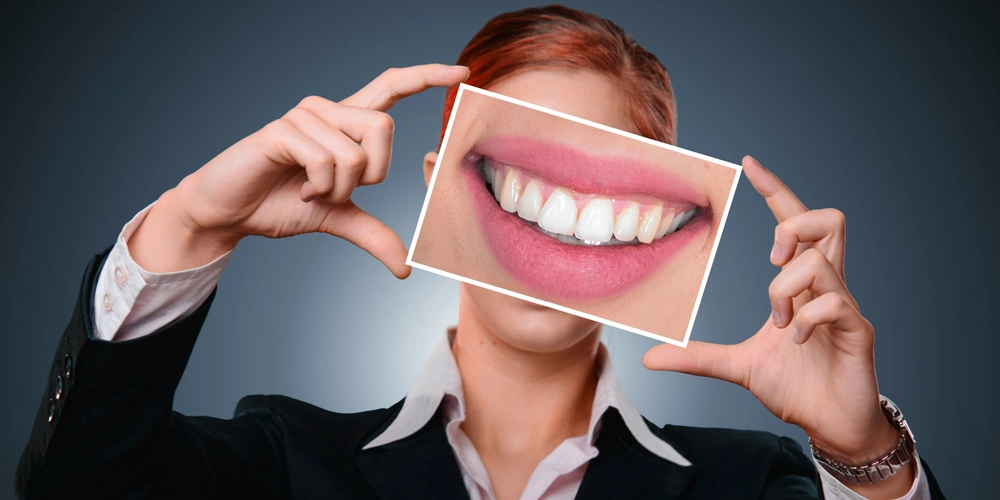 A women holding a photo of her smile after receiving teeth polishing