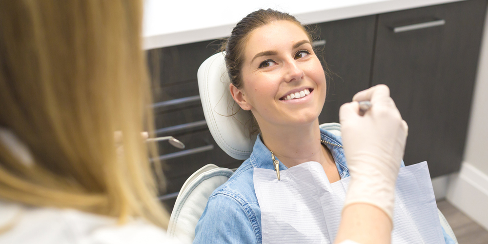 A patient smilng in a dental chair ready to get her composite fillings
