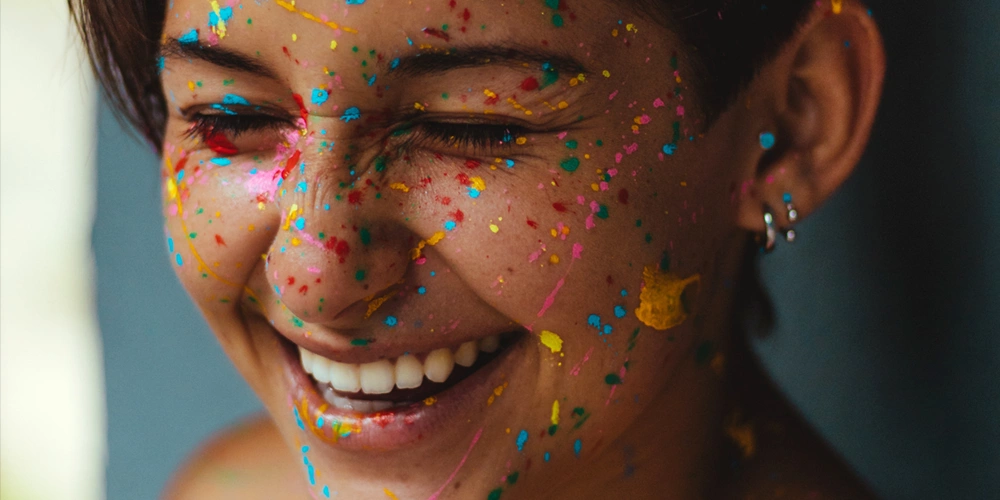 A young girl smiling with paint all over her face after she is finally pain free from her wisdom teeth extractions