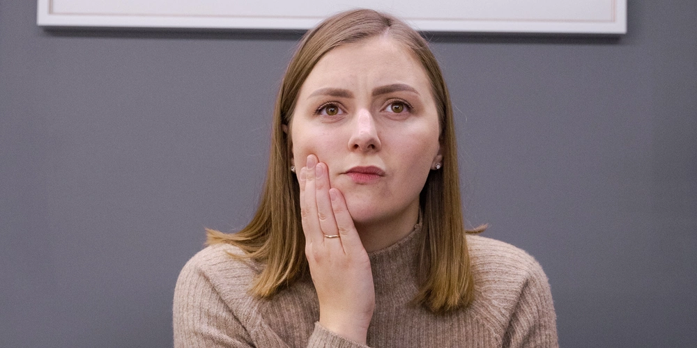 A women holding her jaw and suffering from TMJ Dysfunction Syndrome